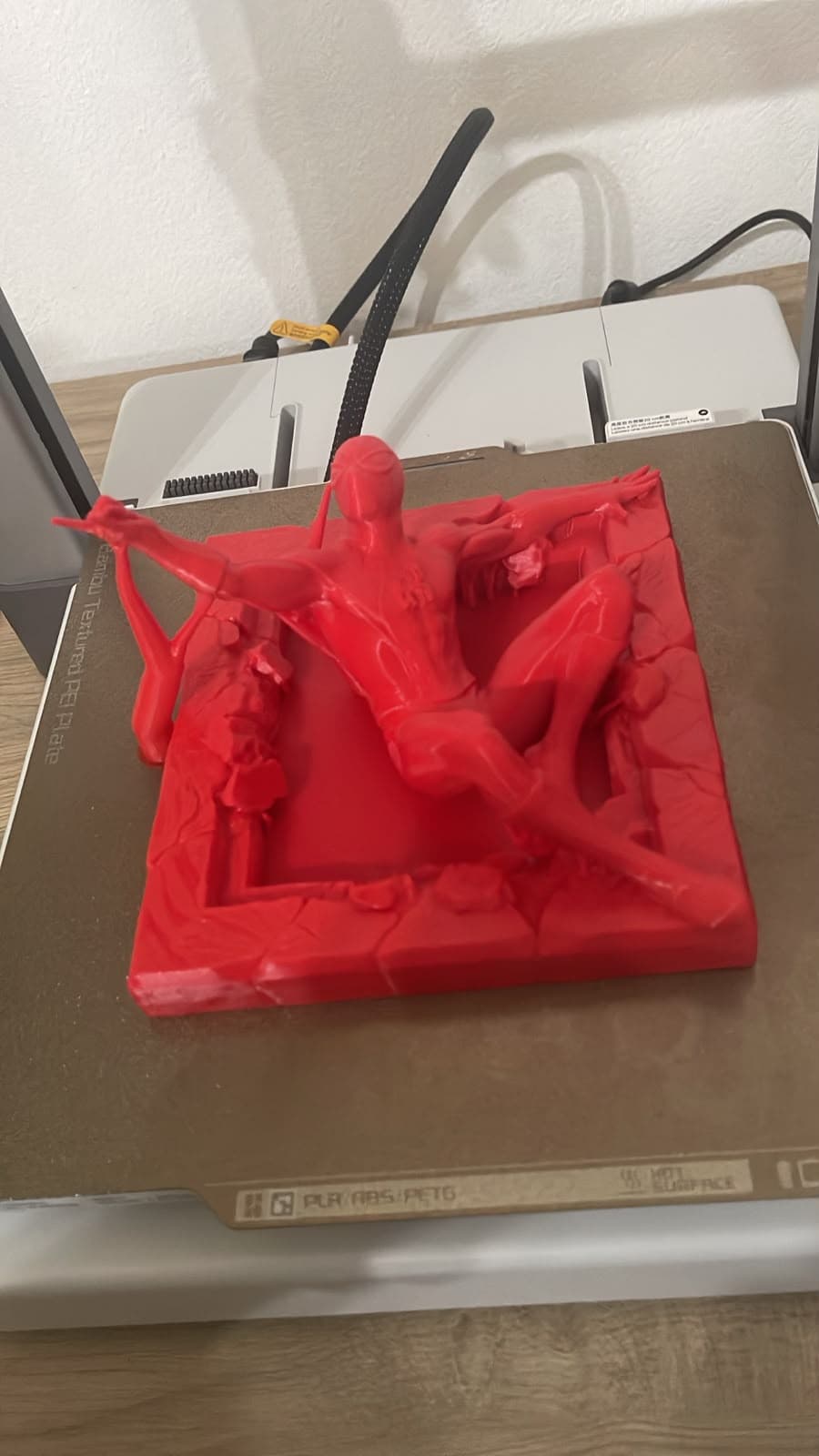 Diorama do Homem-Aranha impresso em 3D em vermelho, com base texturizada